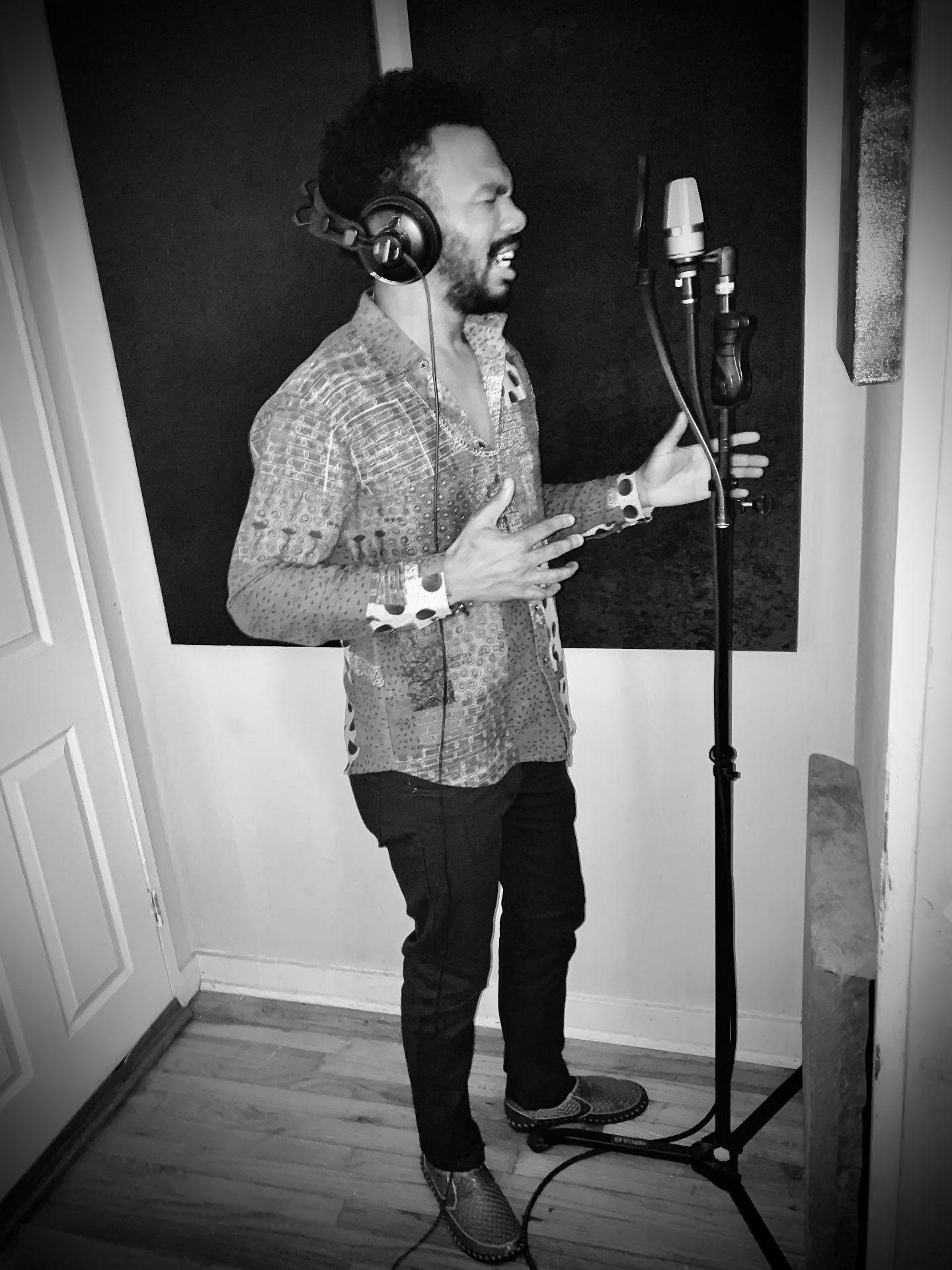 Jerry Stacks singing into a studio microphone with headphones, black and white